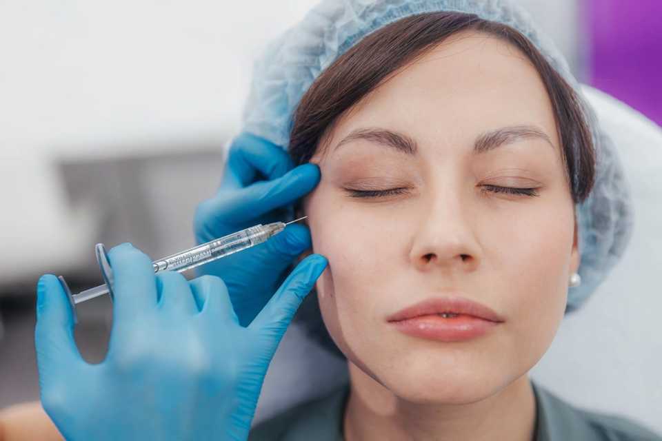 Врач вводит филлер в область скулы