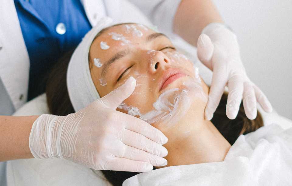 Косметолог наносит специальную маску на лицо