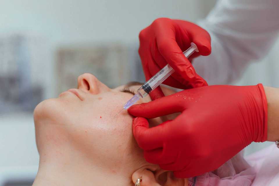 Врач во время проведения мезотерапии вводит препарат в кожу лица